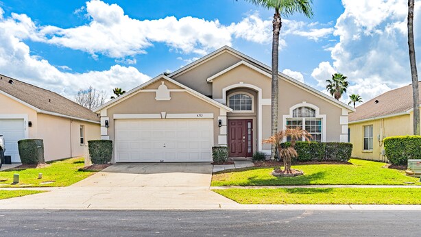 A residential house with a garage, a front yard with a palm tree, and a clear blue sky. - 5BR Villa Private Pool & Game Room (Kissimmee)