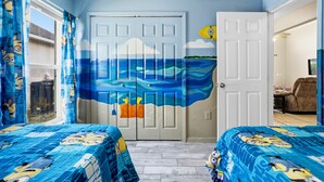 A bedroom with two beds, a door with a mural, and a window with curtains. - 5BR Villa Private Pool & Game Room (Kissimmee)