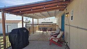 Veranda esterna coperta con una griglia per barbecue, due sedie e un tavolo.