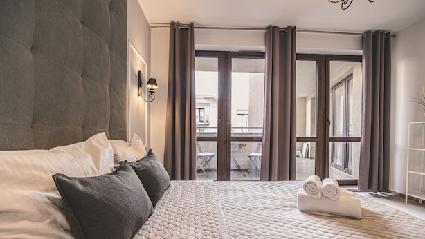 Une chambre avec un grand lit, une lampe de chevet, une vue sur le balcon et un lit bien fait, agrémenté de serviettes.