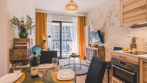 Uma sala de jantar com uma mesa posta para quatro pessoas, uma televisão na parede e vista para o exterior através de uma porta de correr.