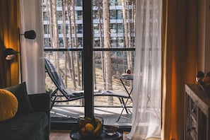 Ein Zimmer mit großem Fenster, einem Sessel, einem kleinen Tisch und einer dekorativen Schale.