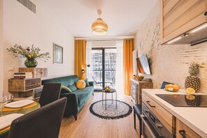 Eine moderne Küche mit Essbereich, einer Couch und Blick durch ein großes Fenster.