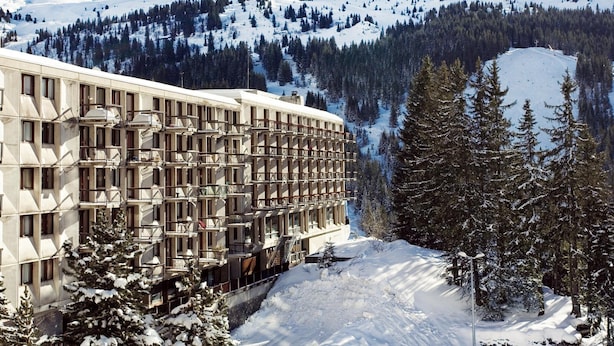 Ett hotell med flera våningar och en modern arkitektonisk design, beläget i ett snötäckt bergområde med utsikt över det omgivande landskapet.