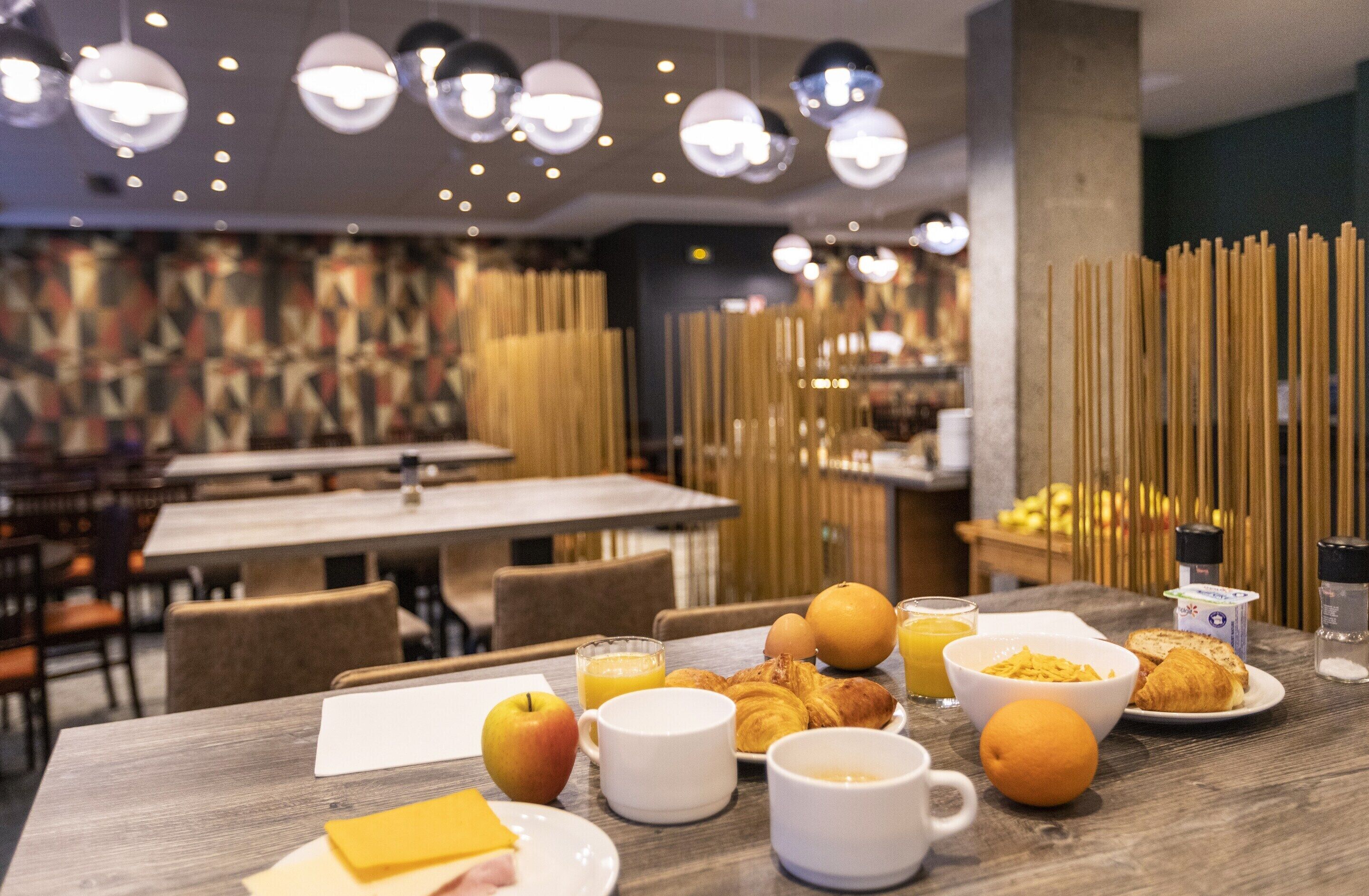 Een ontbijttafel gedekt met croissants, fruit en sinaasappelsap.