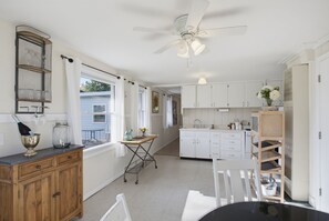 A kitchen with white cabinets, a ceiling fan, and a dining area with a table and chairs.