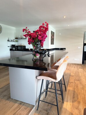 Une cuisine moderne avec un îlot central, des tabourets de bar et un vase rempli de fleurs.
