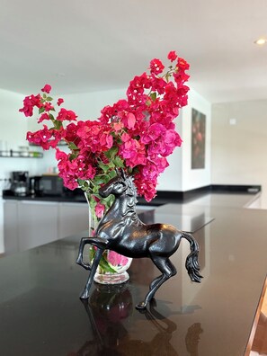 Un vase noir en forme de cheval, orné de fleurs roses sur une surface réfléchissante.