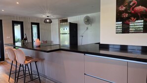 Eine moderne Küche mit schwarzer Arbeitsplatte, weißen Schränken und einem Flamingo-Gemälde.