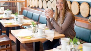 A person seated at a table in a restaurant with wooden logs on the wall and a colorful painting. - Hotel Bad Rappenau (Bad Rappenau)
