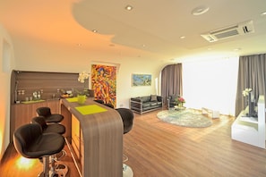 Una habitación de hotel moderna con una zona de bar, asientos y obras de arte.