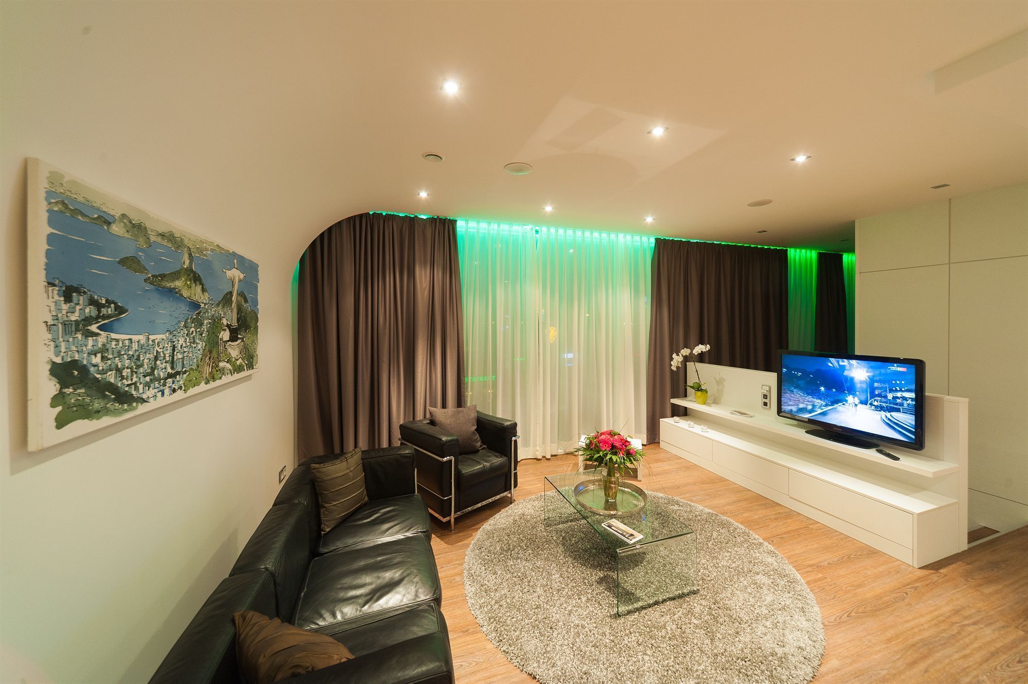 Ein modernes Wohnzimmer mit einer Ledersofa, einem Glastisch, einem Flachbildfernseher und einem Stadtbild.