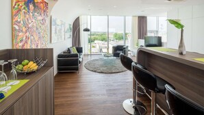 A modern hotel room with a large window, a bar area, a sofa, and a dining table. - Hotel Bad Rappenau (Bad Rappenau)