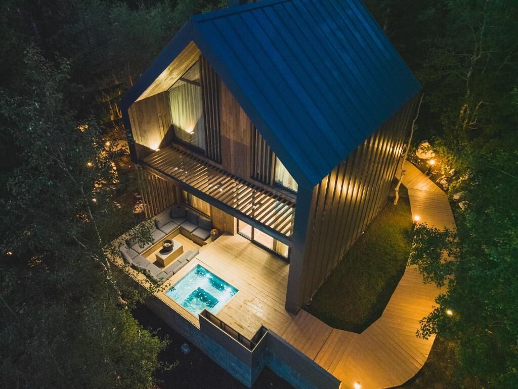 A modern house with a swimming pool, wooden deck, and a large window overlooking the landscape.