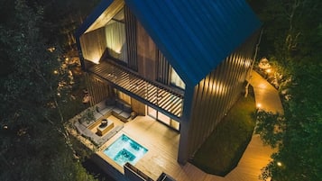 A modern house with a swimming pool, wooden deck, and a large window overlooking the landscape.