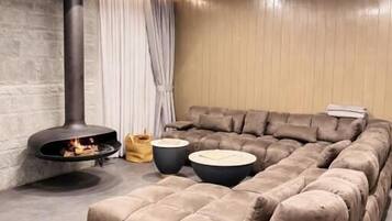 A modern living room with a sectional sofa, a fireplace, and a large window with curtains.
