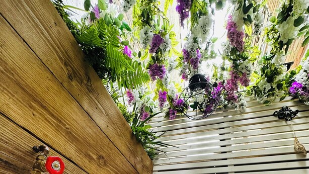 Eine Badewanne mit einem Glas Champagner, Holzvertäfelung und hängenden Blumen.