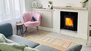 Ein modernes Wohnzimmer mit Kamin, einer Couch, einem Sessel und dekorativen Regalen.