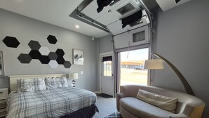 A bedroom with a bed, a sofa, a wall with hexagonal decorations, and a door leading outside. - New Modern Studio in Maryville (Maryville)