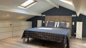 A bedroom with a sloped ceiling, skylights, a bed with a checkered bedspread, and built-in storage cabinets. - Charming air-conditioned house in a quiet area - Sospel (Sospel)