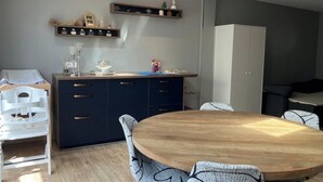 A modern kitchen with a round wooden table, dark blue cabinets, and a hanging light fixture. - Charming air-conditioned house in a quiet area - Sospel (Sospel)