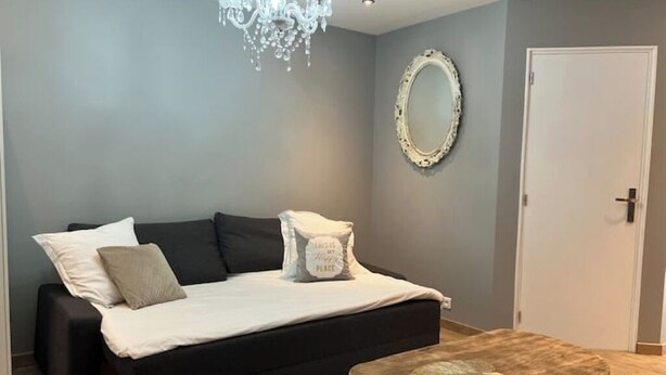 A room with a bed, a round wooden table, a chandelier, a mirror, and a door. - Charming air-conditioned house in a quiet area - Sospel (Sospel)
