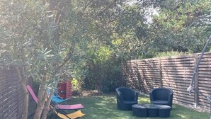 A backyard with a wooden fence, a small tree, and outdoor furniture including two chairs and a table. - Charming air-conditioned house in a quiet area - Sospel (Sospel)