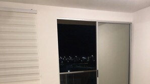 A balcony with a chair, a sliding glass door, and a view of a cityscape at night. - Luxury apartment in serena del mar (Cartagena)