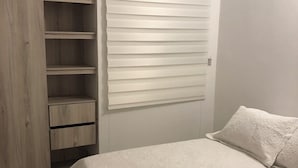 A bedroom with a bed, a wardrobe, and a window with blinds. - Luxury apartment in serena del mar (Cartagena)