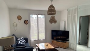 A living room with a sofa, a coffee table, a TV, and a hanging light fixture. - TY BIHAN ☀️ (Crozon)