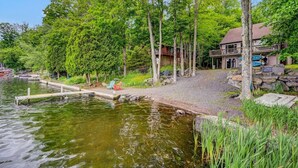 Ein Seehaus mit Steg, umgeben von Bäumen und einem Steinweg, der zum Eingang führt.