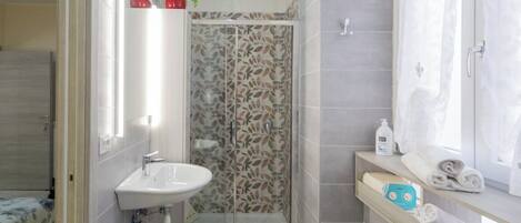 Un baño con ducha, lavamanos e inodoro.