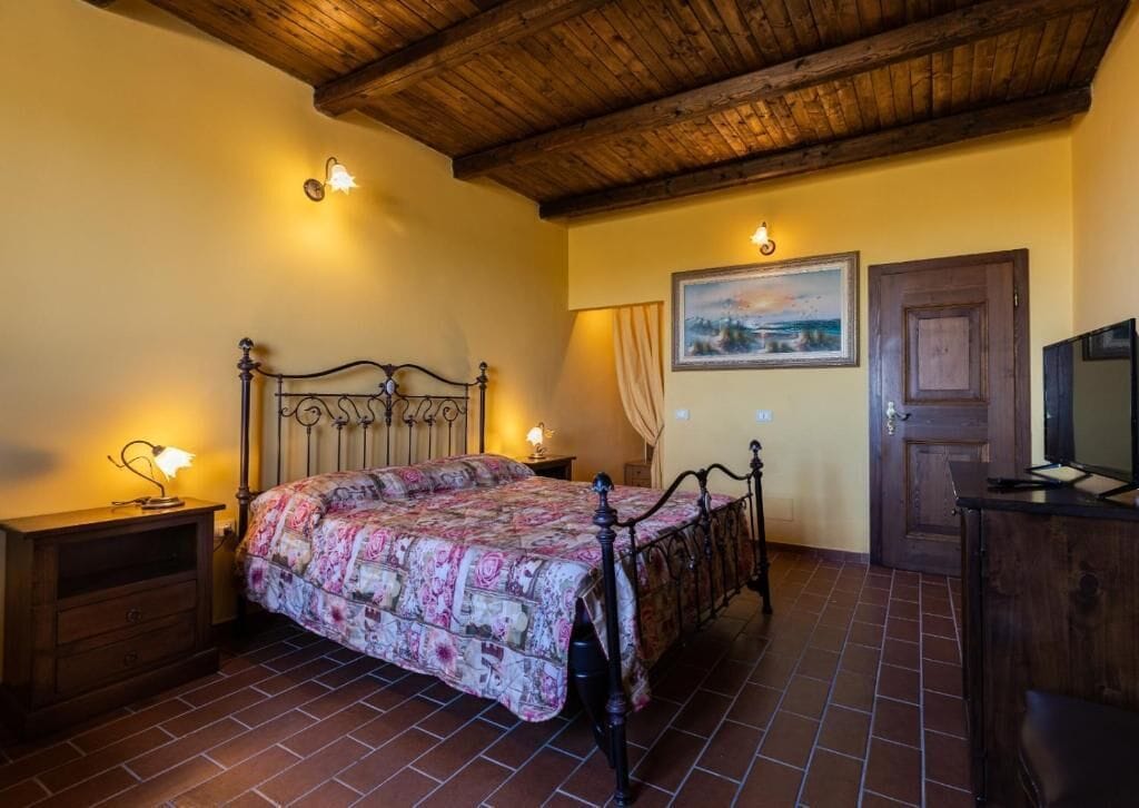 Una camera da letto con un letto, una testiera in legno, due comodini, un tavolino e un quadro appeso al muro.