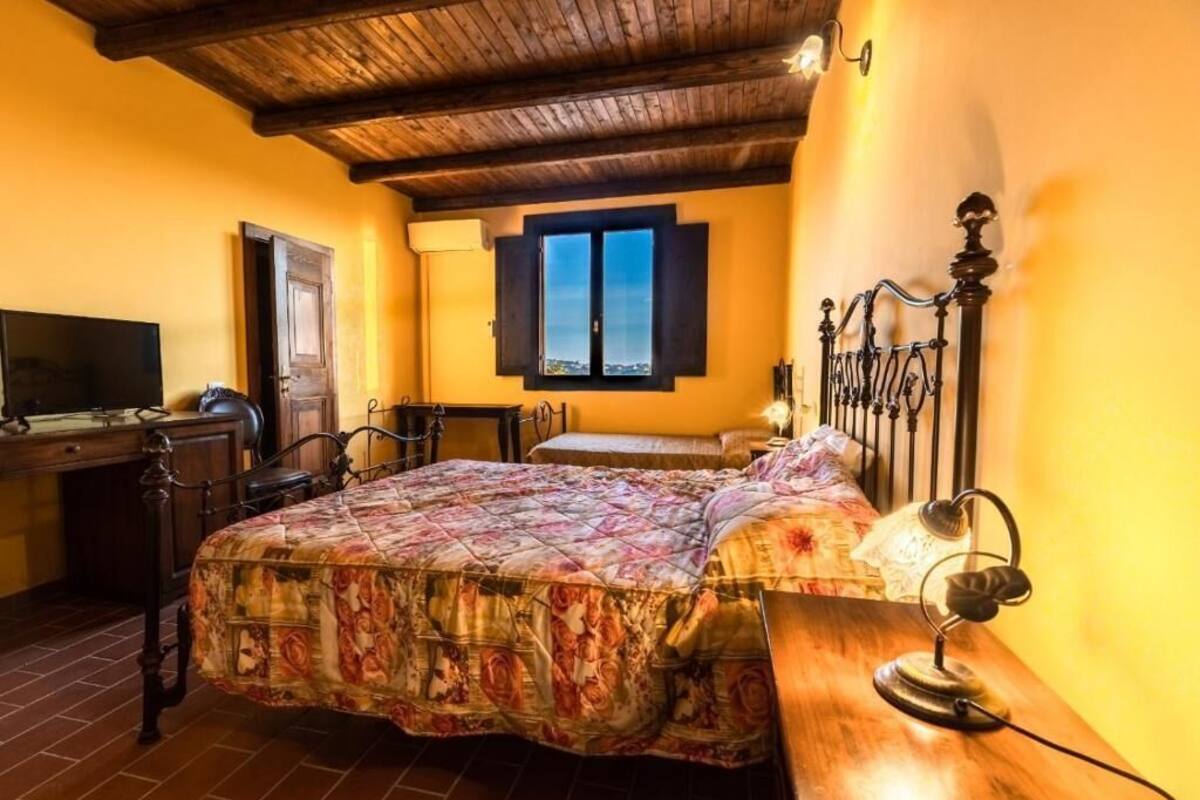 A bedroom with a bed, a desk, a chair, a window, and a lamp.