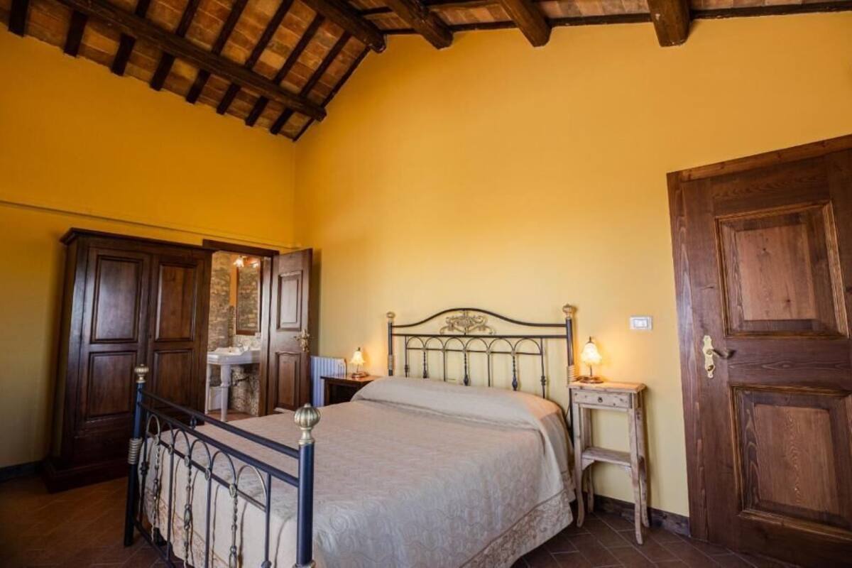A bedroom with a bed, wooden wardrobe, bedside table, and a door.