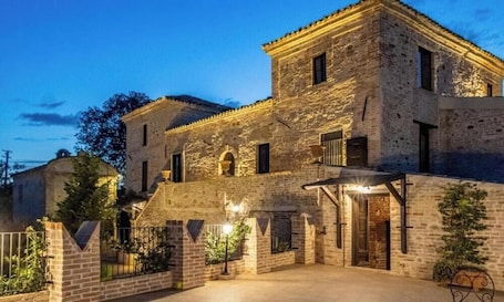 A stone building with multiple levels, a gated entrance, and a small balcony.. Castello di Petecciano