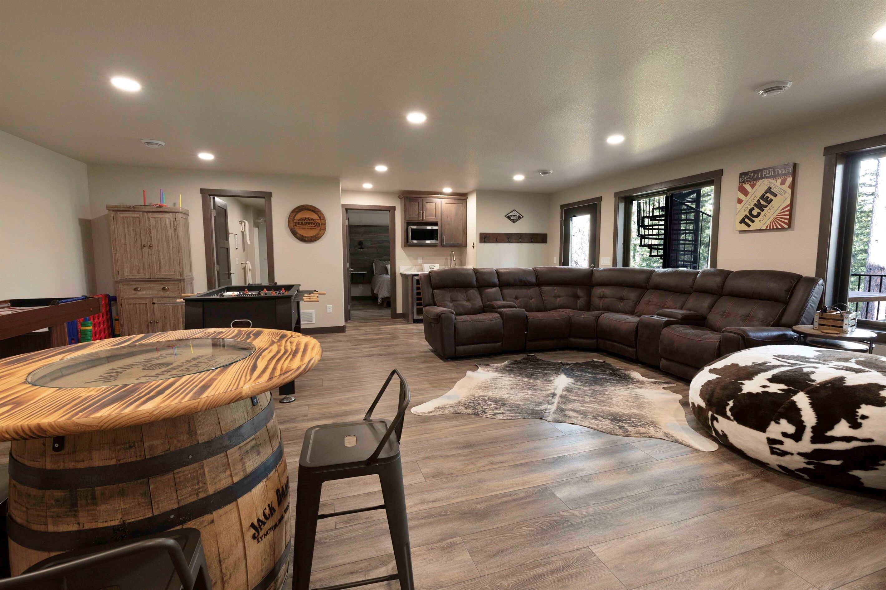 A spacious living area with a sectional sofa, a wooden barrel table, and a cowhide rug.