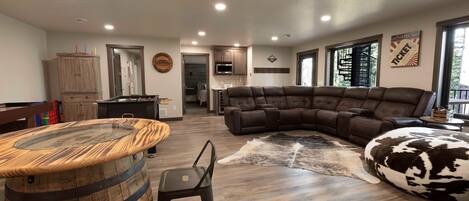 A spacious living area with a sectional sofa, a wooden barrel table, and a cowhide rug.