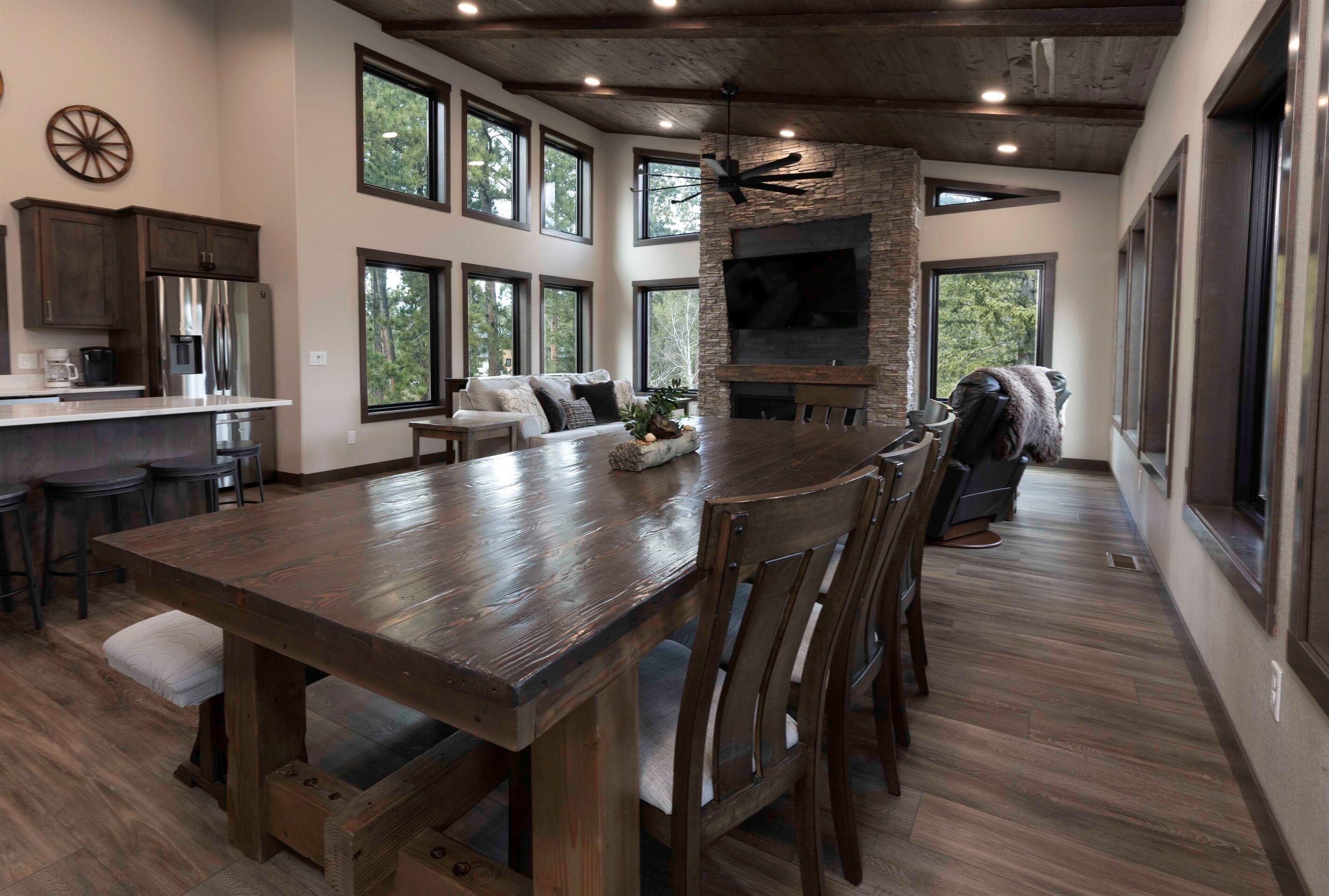 A spacious kitchen with a large island, a stone fireplace, and multiple windows.