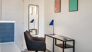 Une pièce moderne comprenant une chaise, une table avec une lampe, un miroir et deux textes encadrés accrochés au mur.