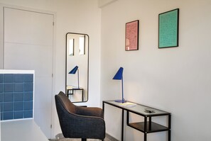 A modern room with a chair, a table with a lamp, a mirror, and two framed texts on the wall. - L'Astrolabe - Studio near Croisette (Cannes)