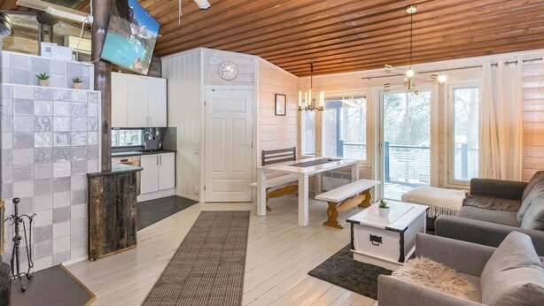 A modern interior with a kitchen, dining area, and living room, featuring wooden floors, a large window, and a television.