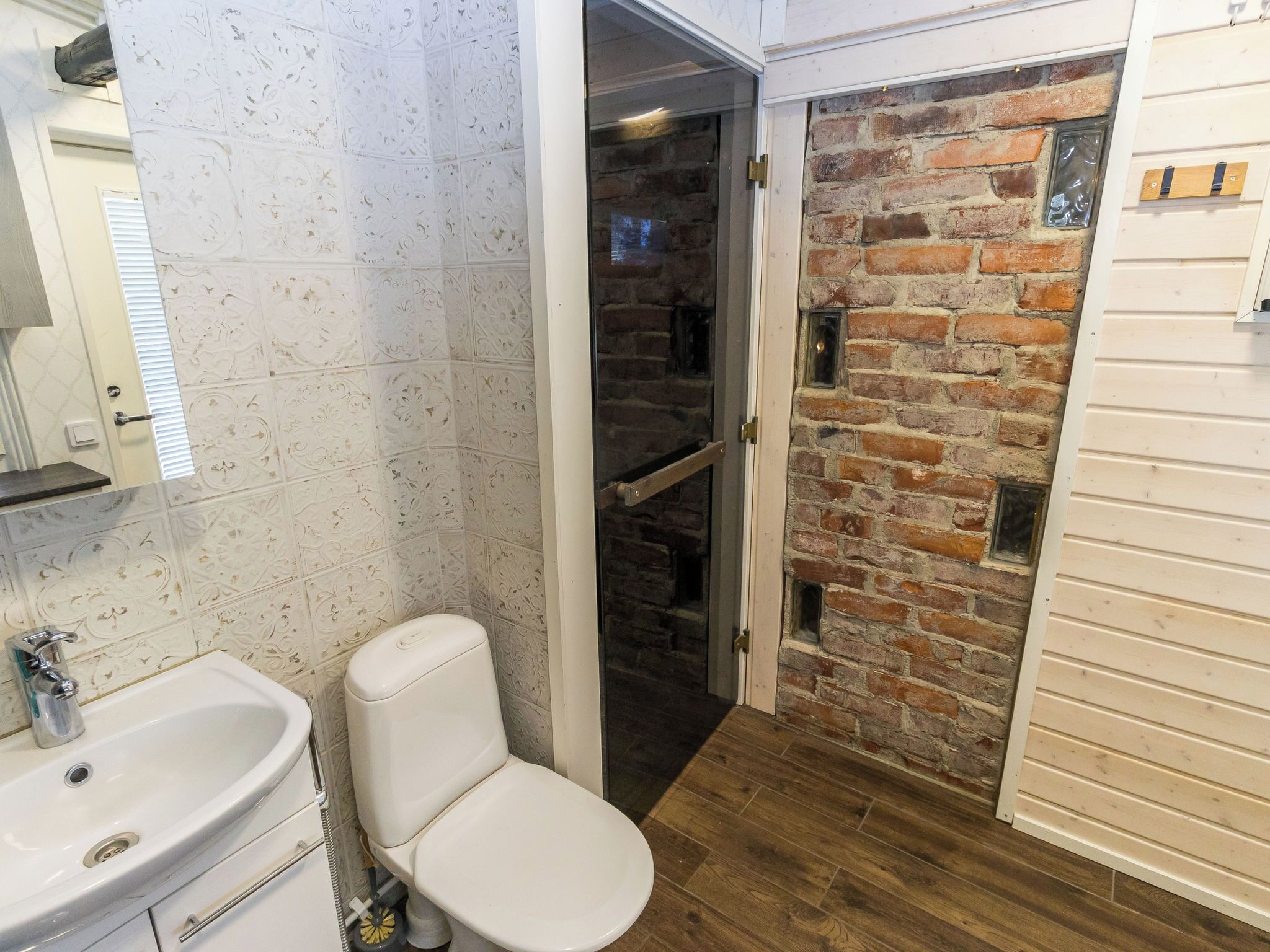 A bathroom with a white sink, toilet, and decorative tiles.