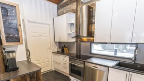 A modern kitchen with white cabinets, stainless steel appliances, and a wooden accent wall.