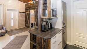 A kitchen with a wooden island, a microwave, a coffee maker, and a refrigerator.