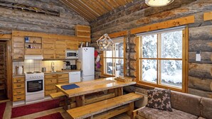 Interior de una cabaña de troncos con cocina, comedor y zona de estar.
