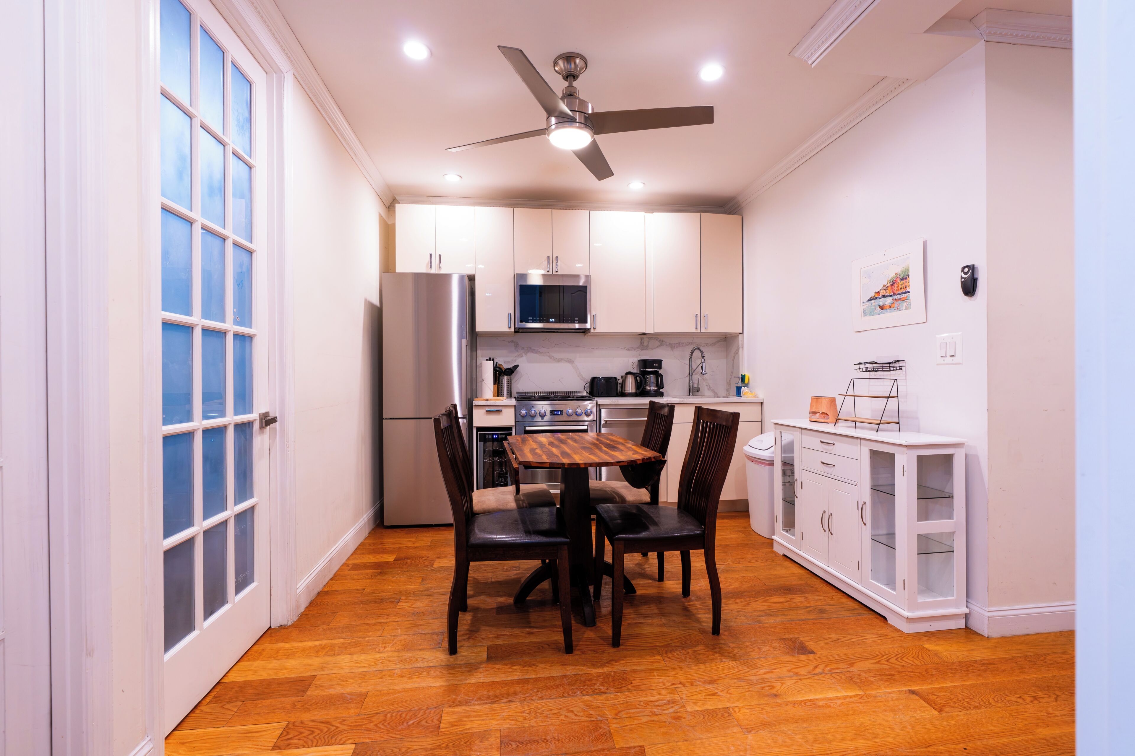 A compact kitchen with a dining table, chairs, and a ceiling fan.