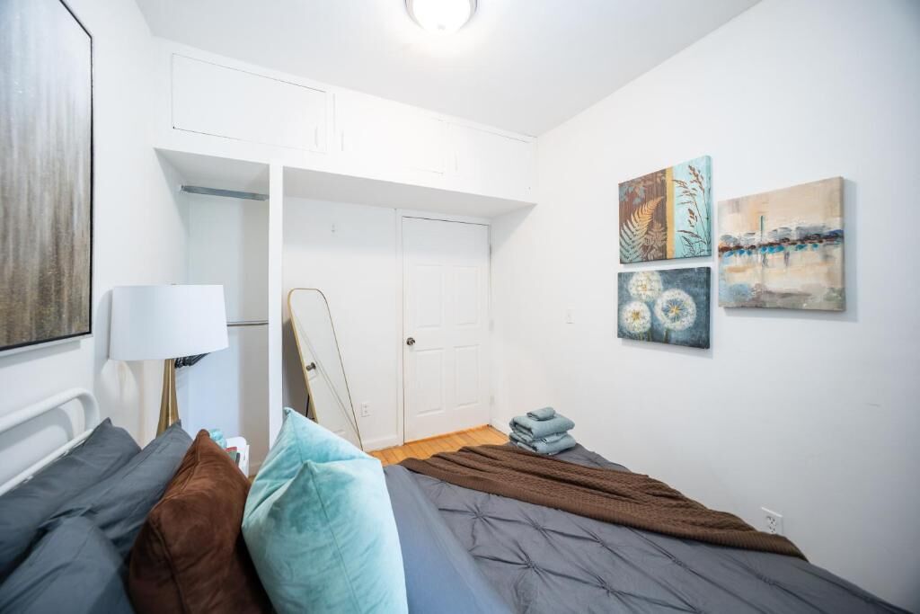 Una camera da letto con un letto, cuscini, una lampada da comodino, un armadio e decorazioni alle pareti.