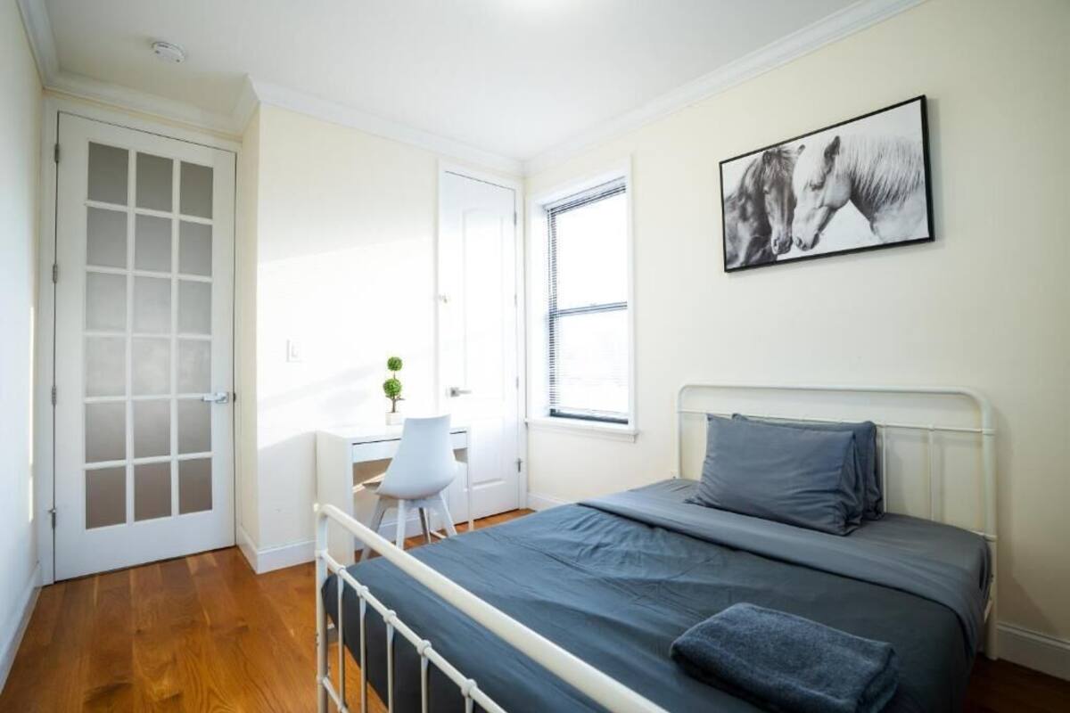 A bedroom with a bed, a desk, and a chair.