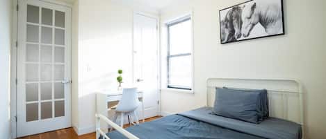 Un dormitorio con una cama, un escritorio y una silla.